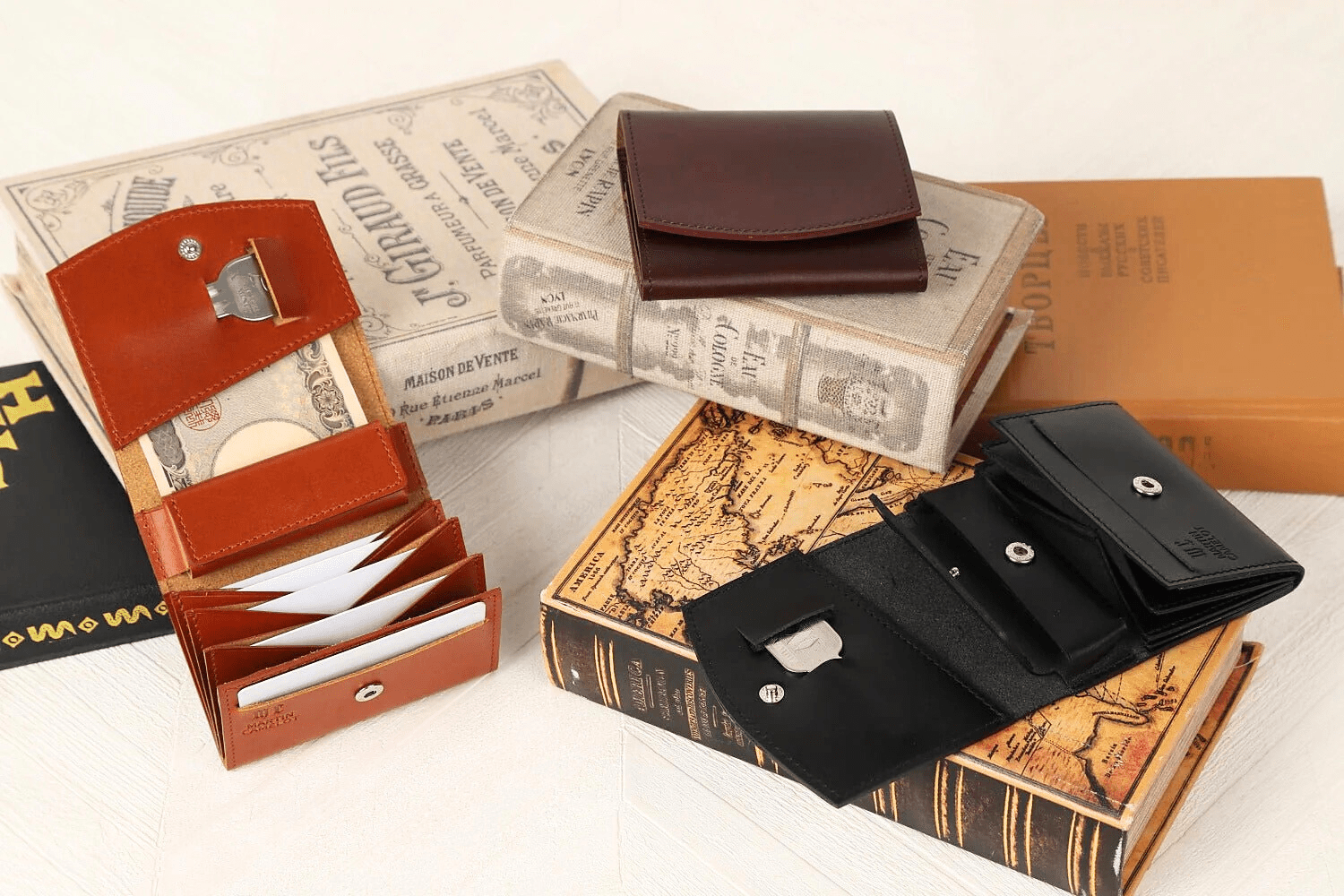 MC-bifoldwallet。蔵前の革職人が製作した国産牛革の薄いコンパクト二つ折り財布。ブラック、バーガンディ、キャメルの3色。平置きして紙幣、カード、鍵の収納イメージ。