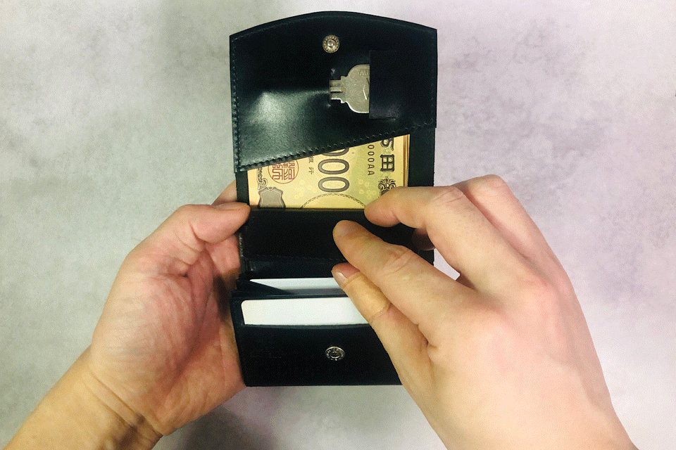 MC-bifoldwallet。蔵前の革職人が製作した国産牛革の薄いコンパクト二つ折り財布。ブラック。小銭を取り出しているGIFアニメーション。