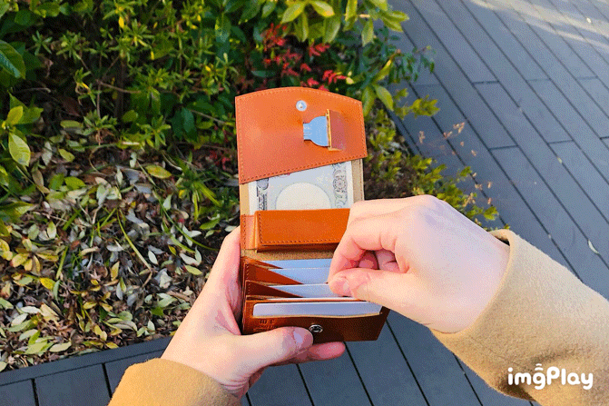 MC-bifoldwallet。蔵前の革職人が製作した国産牛革の蛇腹式コンパクト二つ折り財布。キャメル。カードホルダーからカードを取り出しているGIFアニメーション。