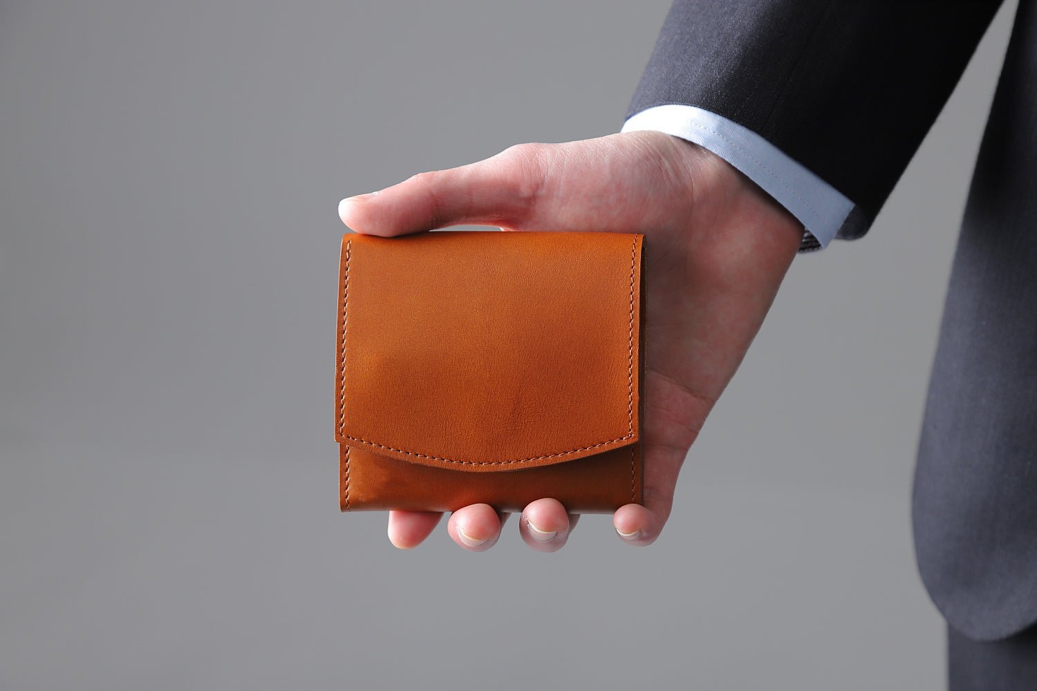 MC-bifoldwallet。蔵前の革職人が製作した国産牛革の薄いコンパクト二つ折り財布。キャメル。財布を手に持ってるシーン。