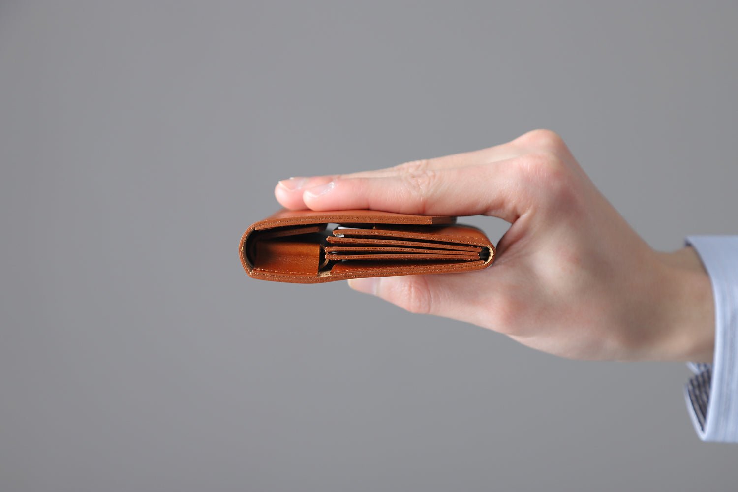 MC-bifoldwallet。蔵前の革職人が製作した国産牛革の薄いコンパクト二つ折り財布。キャメル。財布を水平に持っているシーン