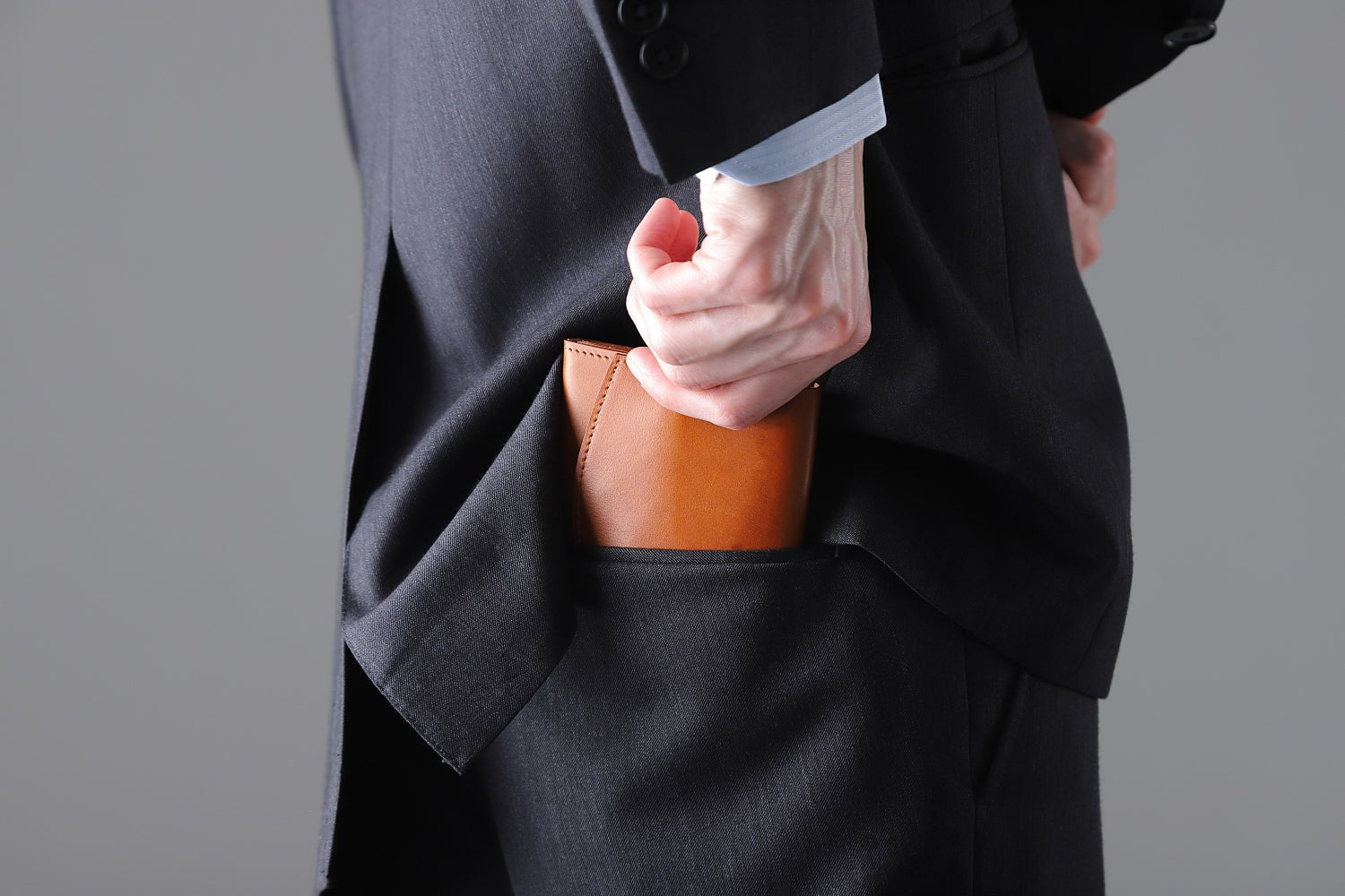 MC-bifoldwallet。蔵前の革職人が製作した国産牛革の薄いコンパクト二つ折り財布。キャメル。財布を後ろポケットにしまうシーン。