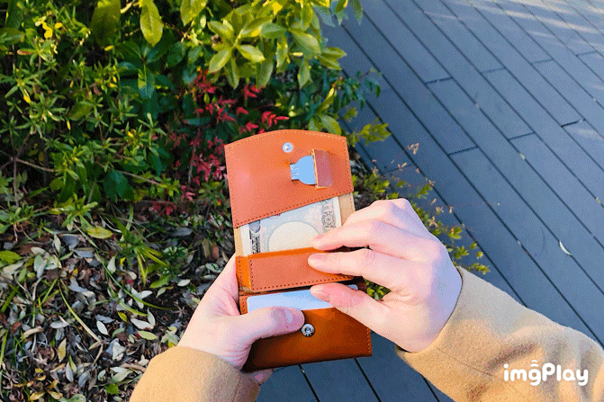 MC-bifoldwallet。蔵前の革職人が製作した国産牛革の蛇腹式コンパクト二つ折り財布。キャメル。小銭を取り出しているGIFアニメーション。