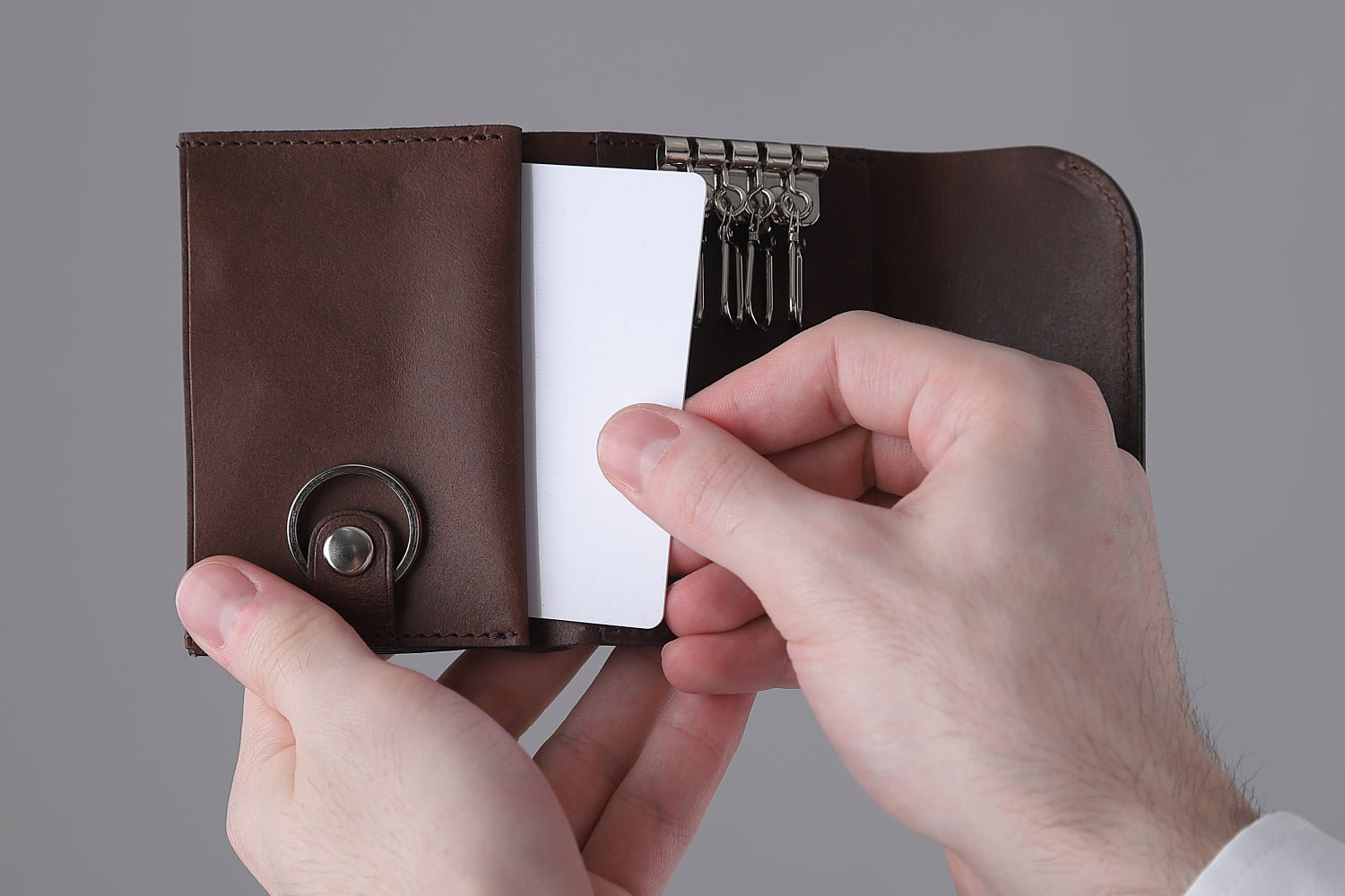 MC-keywallet。蔵前の革職人が製作した国産牛革のキーケース一体型ミニ財布。ダークブラウン。左側ポケットからカードを取り出しているイメージ。