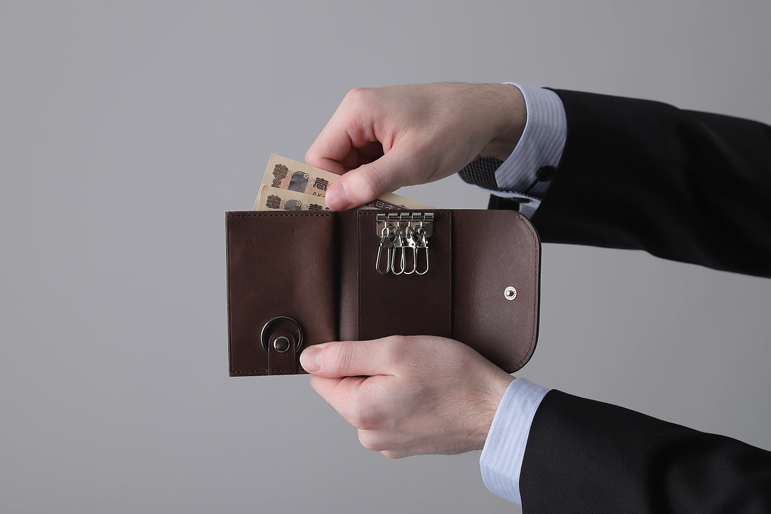 MC-keywallet。蔵前の革職人が製作した国産牛革のキーケース一体型ミニ財布。ダークブラウン。紙幣を取り出しているイメージ。