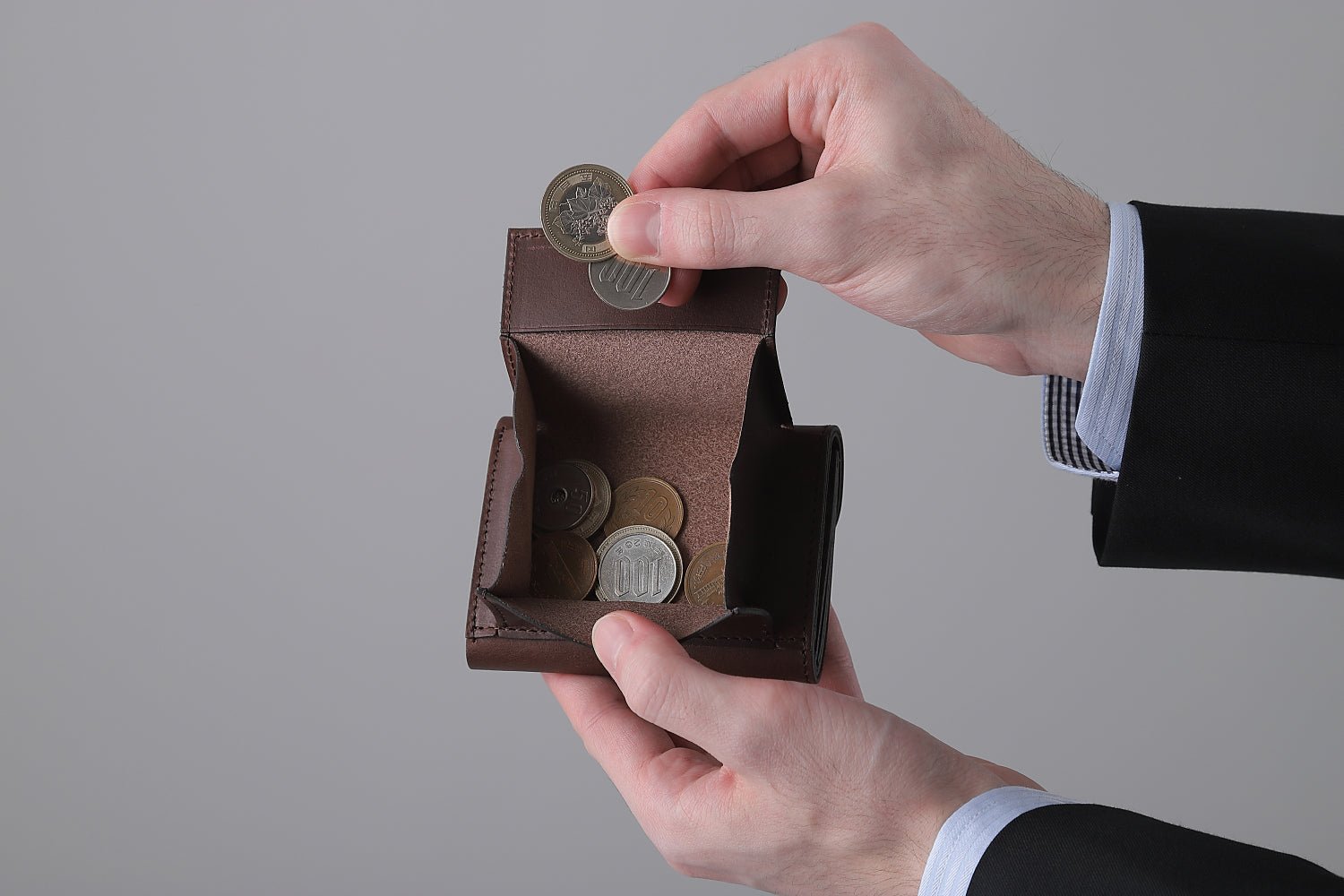 MC-keywallet。蔵前の革職人が製作した国産牛革のキーケース一体型ミニ財布。ダークブラウン。小銭を取り出しているイメージ。