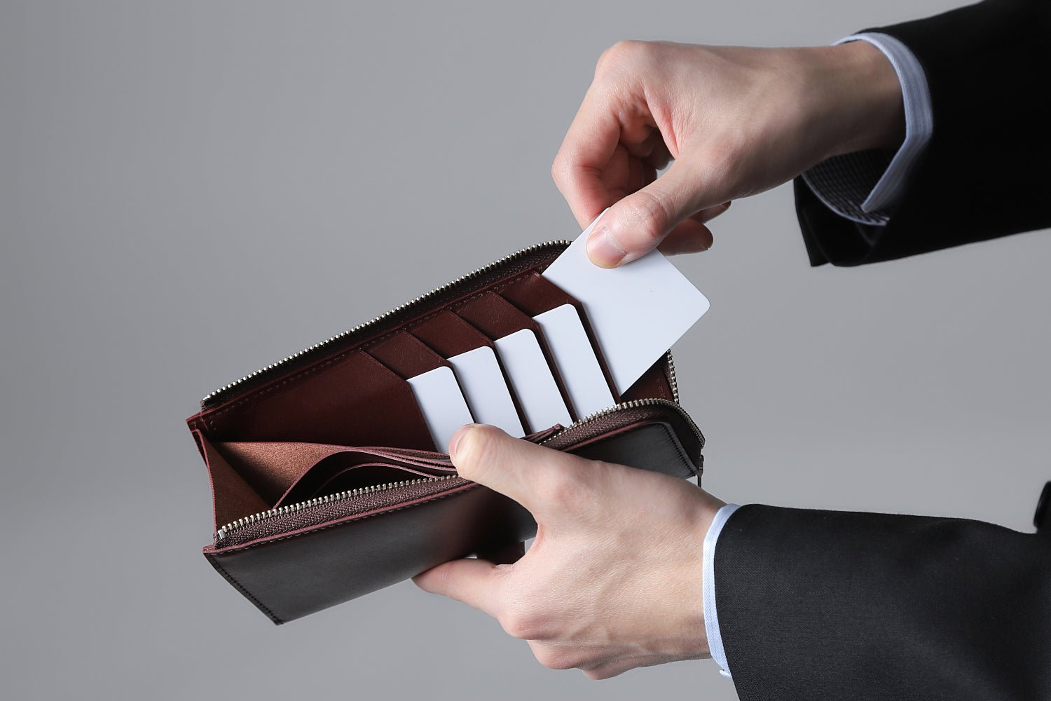 MC-longwallet。蔵前の革職人が製作した国産牛革のL字ファスナーコンパクト長財布。バーガンディ。カードホルダーからカードを取り出しているイメージ。