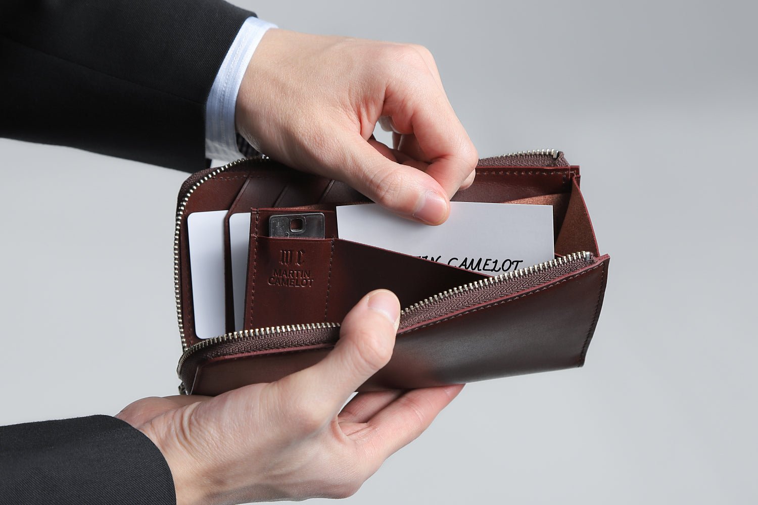 MC-longwallet。蔵前の革職人が製作した国産牛革のL字ファスナーコンパクト長財布。バーガンディ。フリーポケットからカードを取り出しているイメージ。