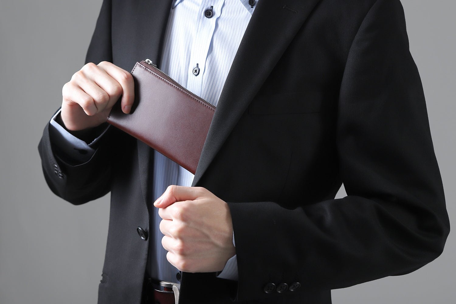 MC-longwallet。蔵前の革職人が製作した国産牛革のL字ファスナーコンパクト長財布。バーガンディ。財布を胸ポケットにしまうシーン。