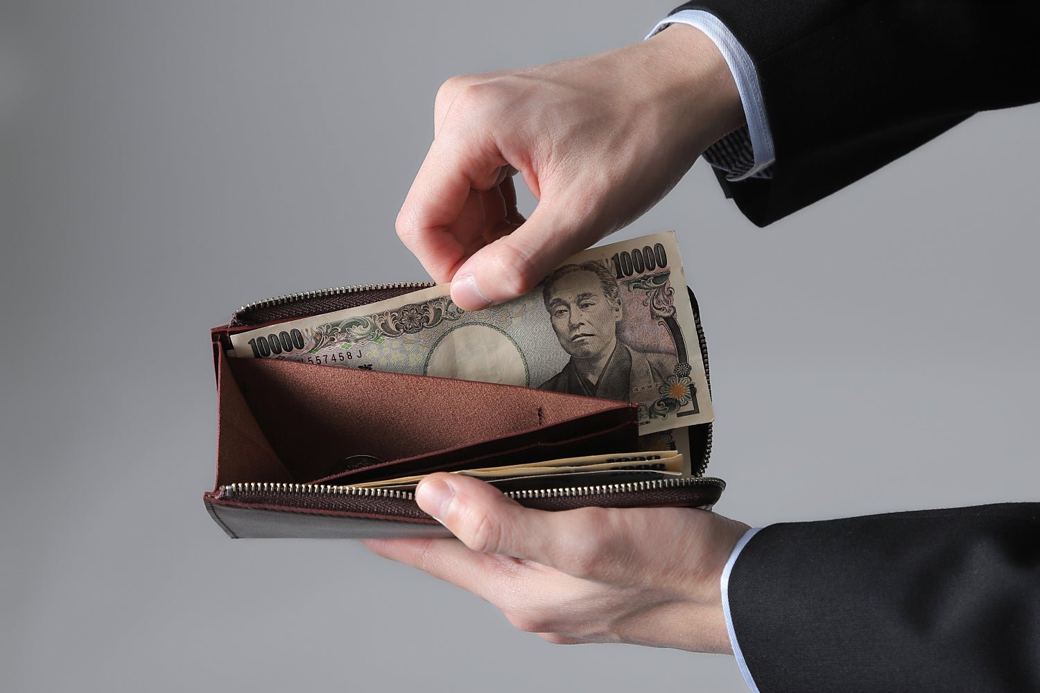 MC-longwallet。蔵前の革職人が製作した国産牛革のL字ファスナーコンパクト長財布。バーガンディ。紙幣を取り出しているイメージ。