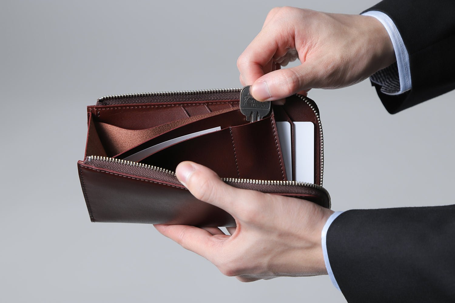 MC-longwallet。蔵前の革職人が製作した国産牛革のL字ファスナーコンパクト長財布。バーガンディ。鍵を取り出しているイメージ。