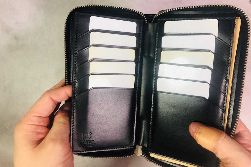 MC-longwallet2。蔵前の革職人が製作した国産牛革のラウンドファスナーコンパクト長財布。ブラック。小銭を取り出しているGIFアニメーション。