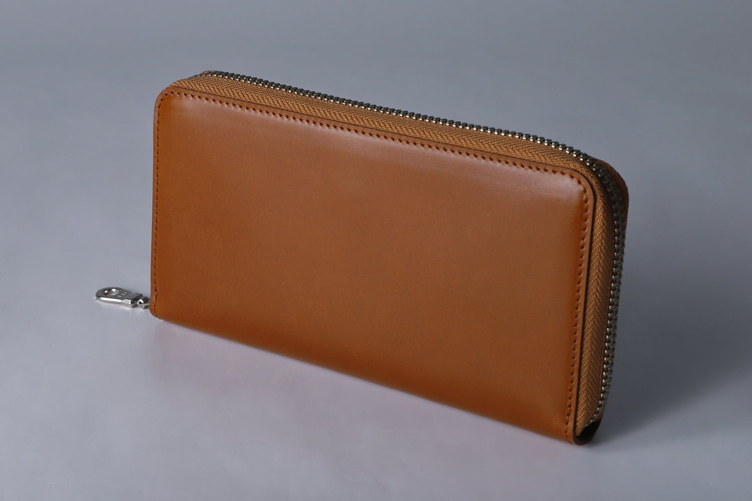 MC-longwallet2。蔵前の革職人が製作した国産牛革のラウンドファスナーコンパクト長財布。キャメル。斜めのイメージ。