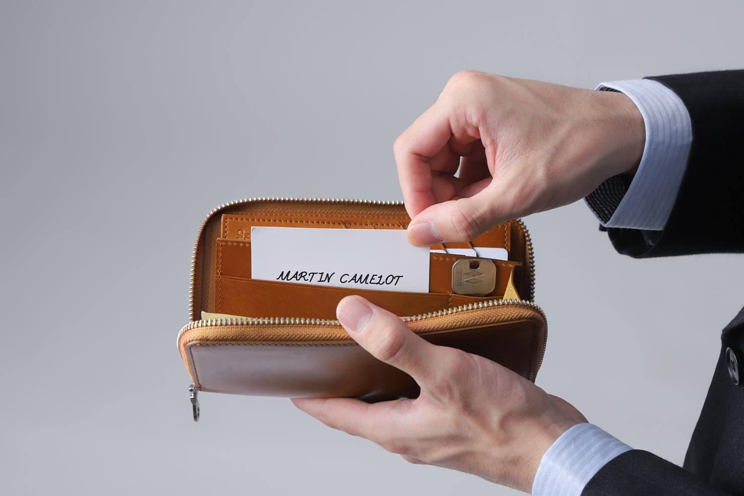 MC-longwallet2。蔵前の革職人が製作した国産牛革のラウンドファスナーコンパクト長財布。キャメル。フリーポケットからカードを取り出しているイメージ。