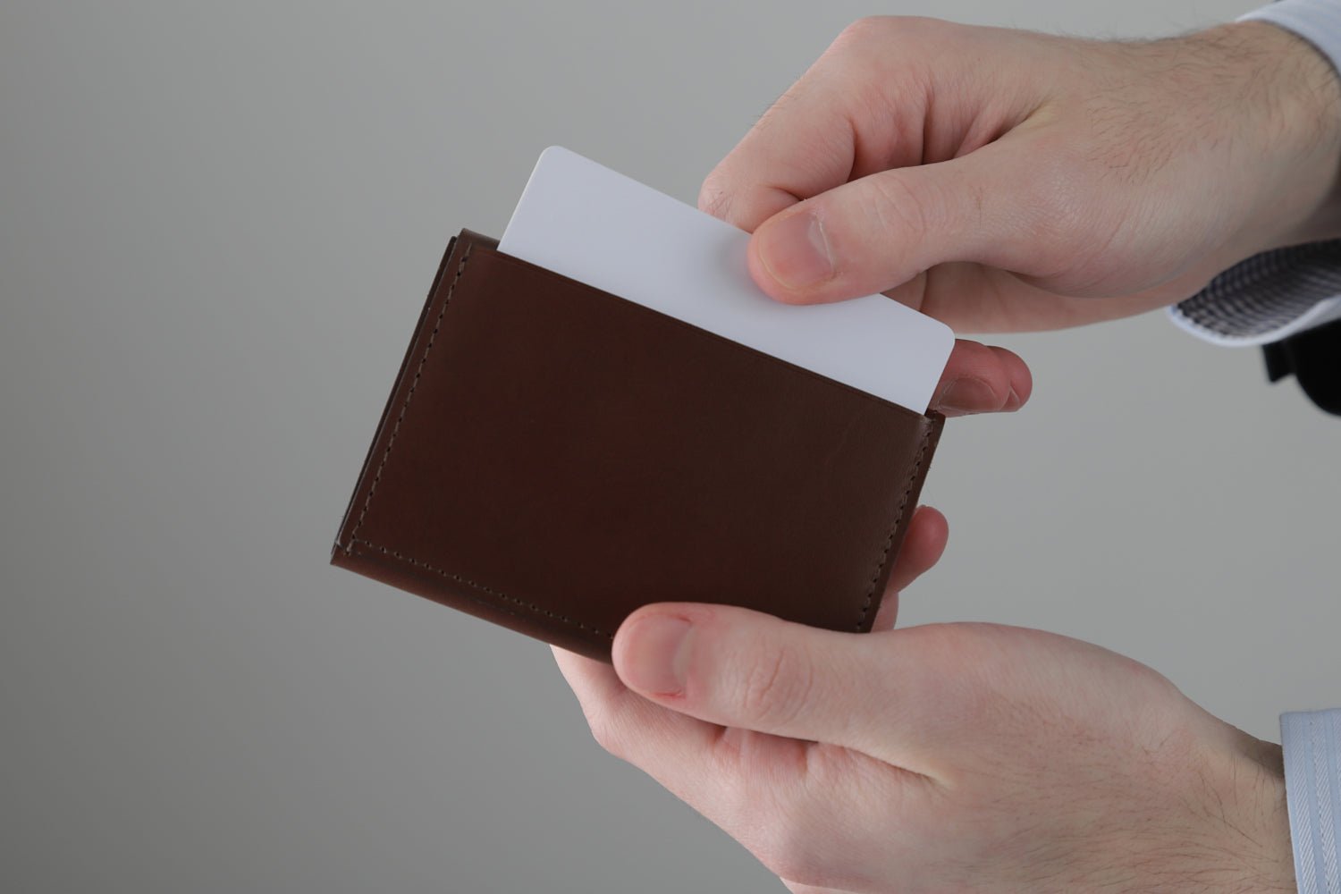 MC-miniwallet。蔵前の革職人が製作した国産牛革のミニ財布。ブラウン。裏面ポケットからカードを取り出しているイメージ。