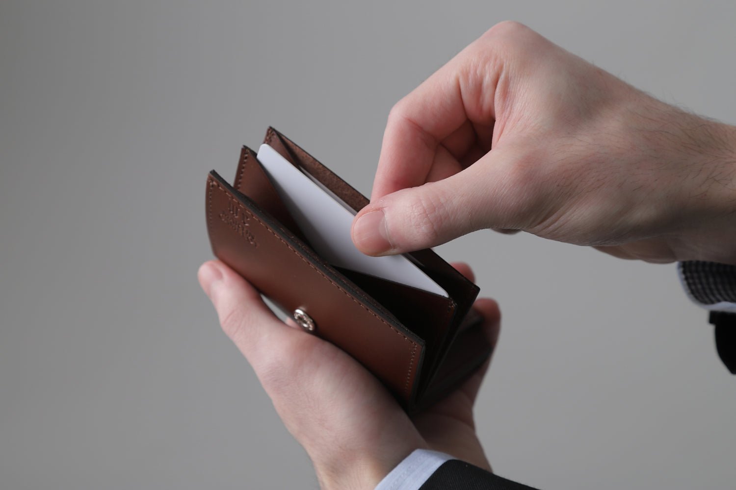 MC-miniwallet。蔵前の革職人が製作した国産牛革のミニ財布。ブラウン。カードホルダーからカードを取り出しているイメージ。