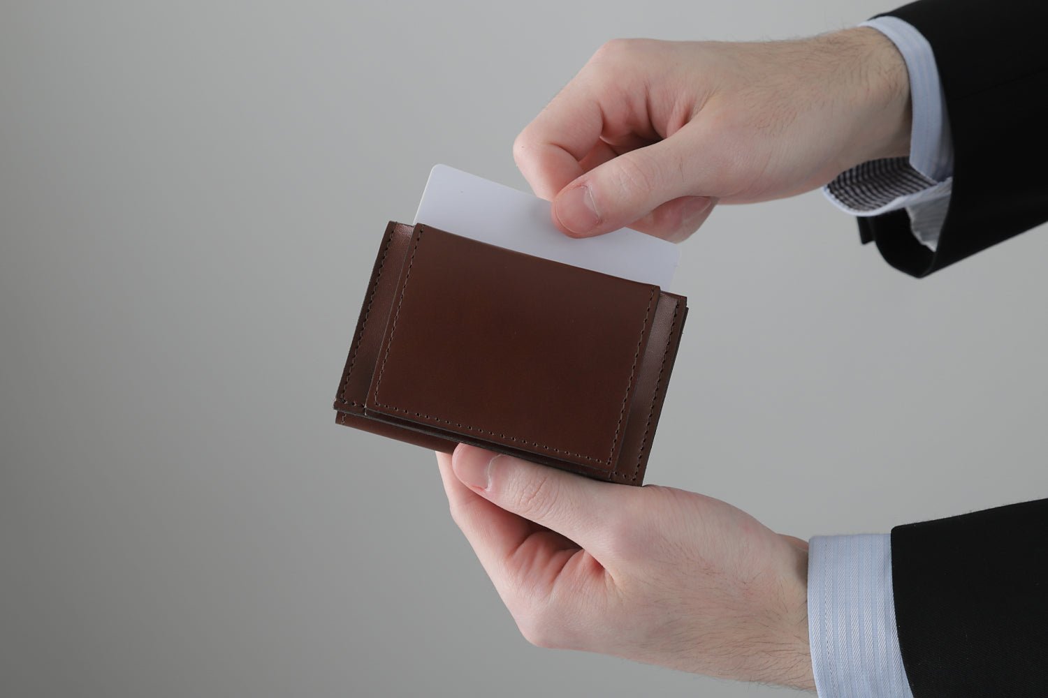 MC-miniwallet。蔵前の革職人が製作した国産牛革のミニ財布。ブラウン。表面ポケットからカードを取り出しているイメージ。