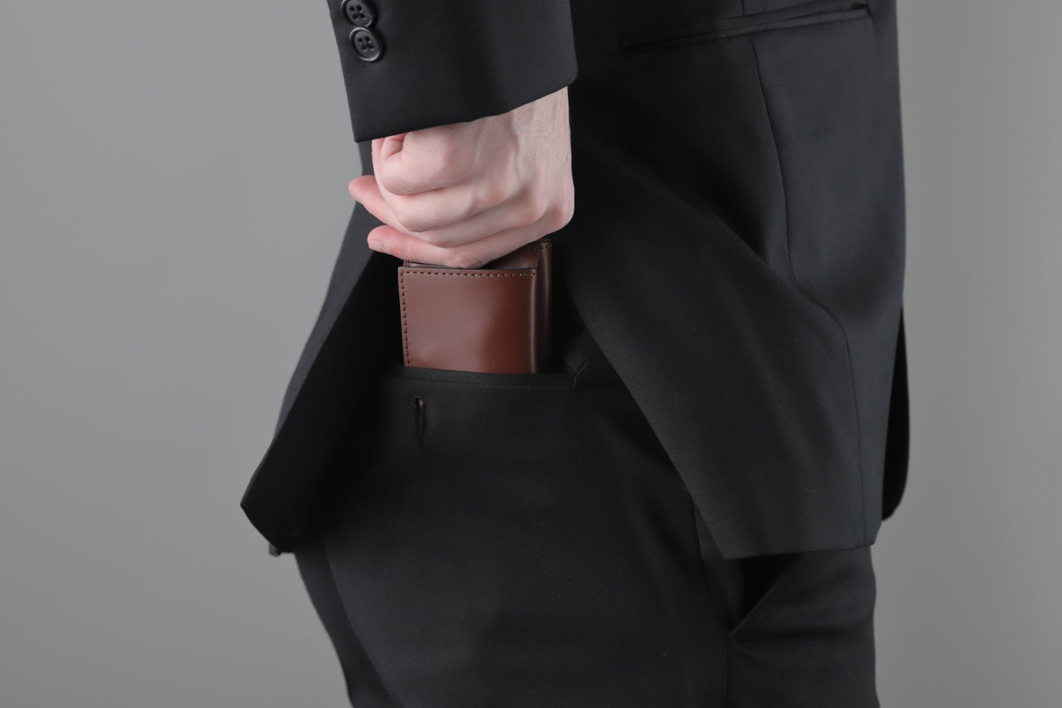 MC-miniwallet。蔵前の革職人が製作した国産牛革のミニ財布。ブラウン。財布を後ろポケットにしまうシーン。