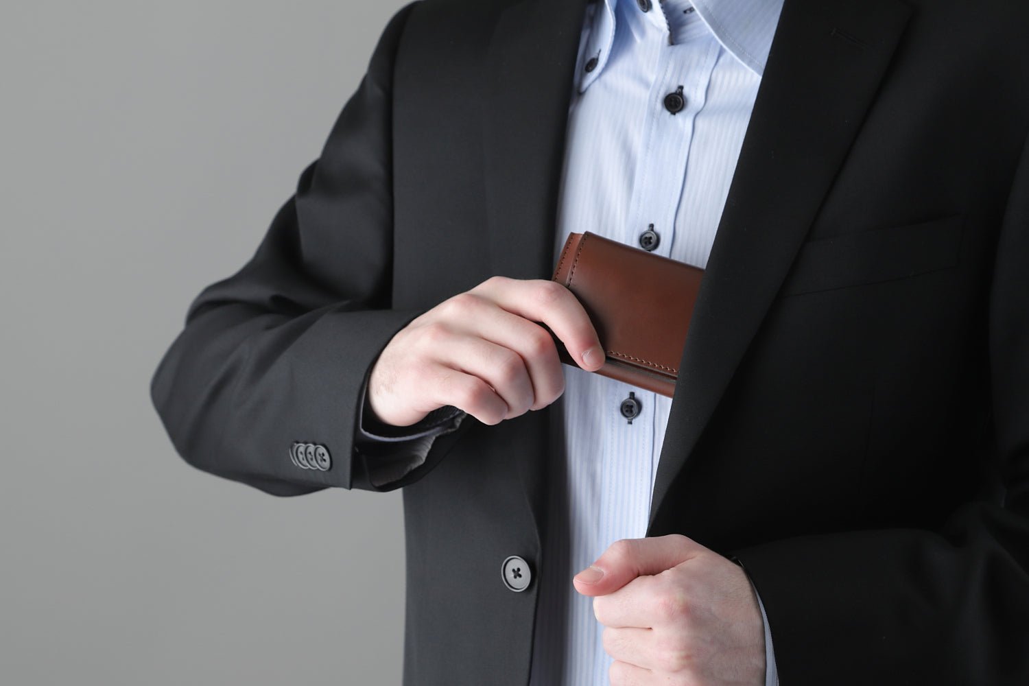 MC-miniwallet。蔵前の革職人が製作した国産牛革のミニ財布。ブラウン。財布を胸ポケットにしまうシーン。