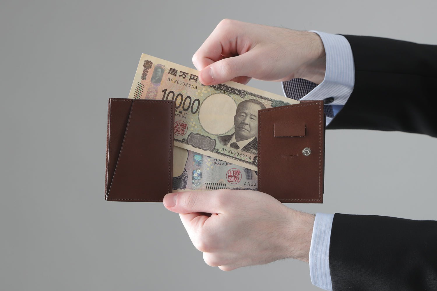 MC-miniwallet。蔵前の革職人が製作した国産牛革のミニ財布。ブラウン。紙幣を取り出しているイメージ。