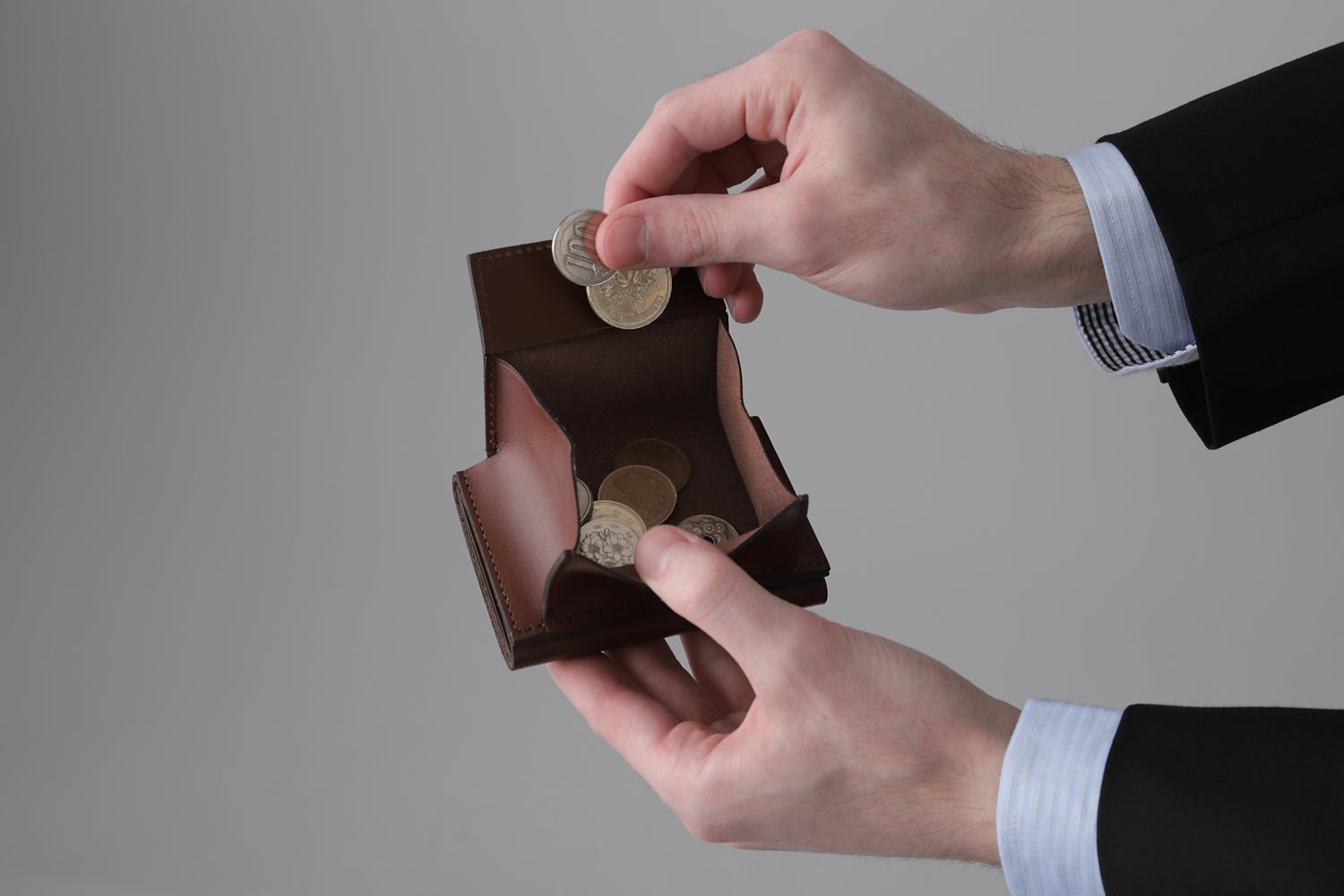 MC-miniwallet。蔵前の革職人が製作した国産牛革のミニ財布。ブラウン。小銭を取り出しているイメージ。