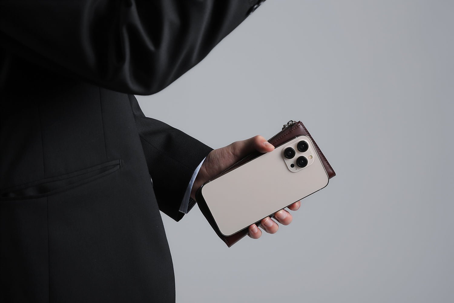 MC-longwallet。蔵前の革職人が製作した国産牛革のL字ファスナーコンパクト長財布。バーガンディ。財布とスマホを持ち合わせしているシーン。