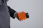 MC-bifoldwallet。蔵前の革職人が製作した国産牛革の蛇腹式コンパクト二つ折り財布。キャメル。財布とスマホを持ち合わせしているシーン。
