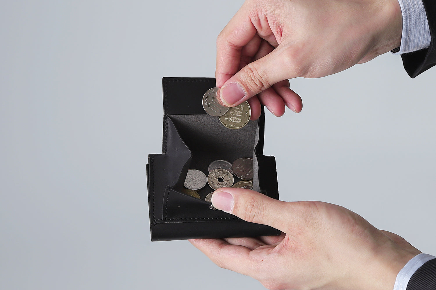 MC-compactwallet。蔵前の革職人が製作した国産牛革のコンパクト財布。ブラック。紙幣を取り出しているイメージ。