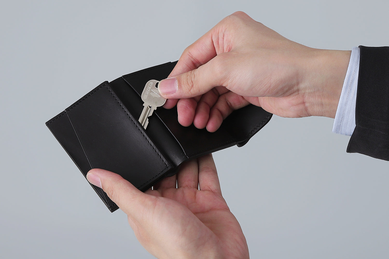 MC-compactwallet。蔵前の革職人が製作した国産牛革のコンパクト財布。ブラック。鍵を取り出しているイメージ。