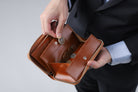 MC-longwallet2。蔵前の革職人が製作した国産牛革のラウンドファスナーミニマル長財布。キャメル。小銭を取り出しているイメージ。